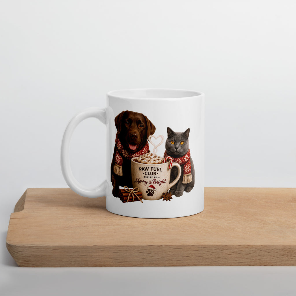 Paw Fuel Club Merry & Bright ceramic coffee mug featuring a Chocolate Labrador and British Shorthair cat wearing festive scarves beside a Christmas coffee mug by Paw Print Society.