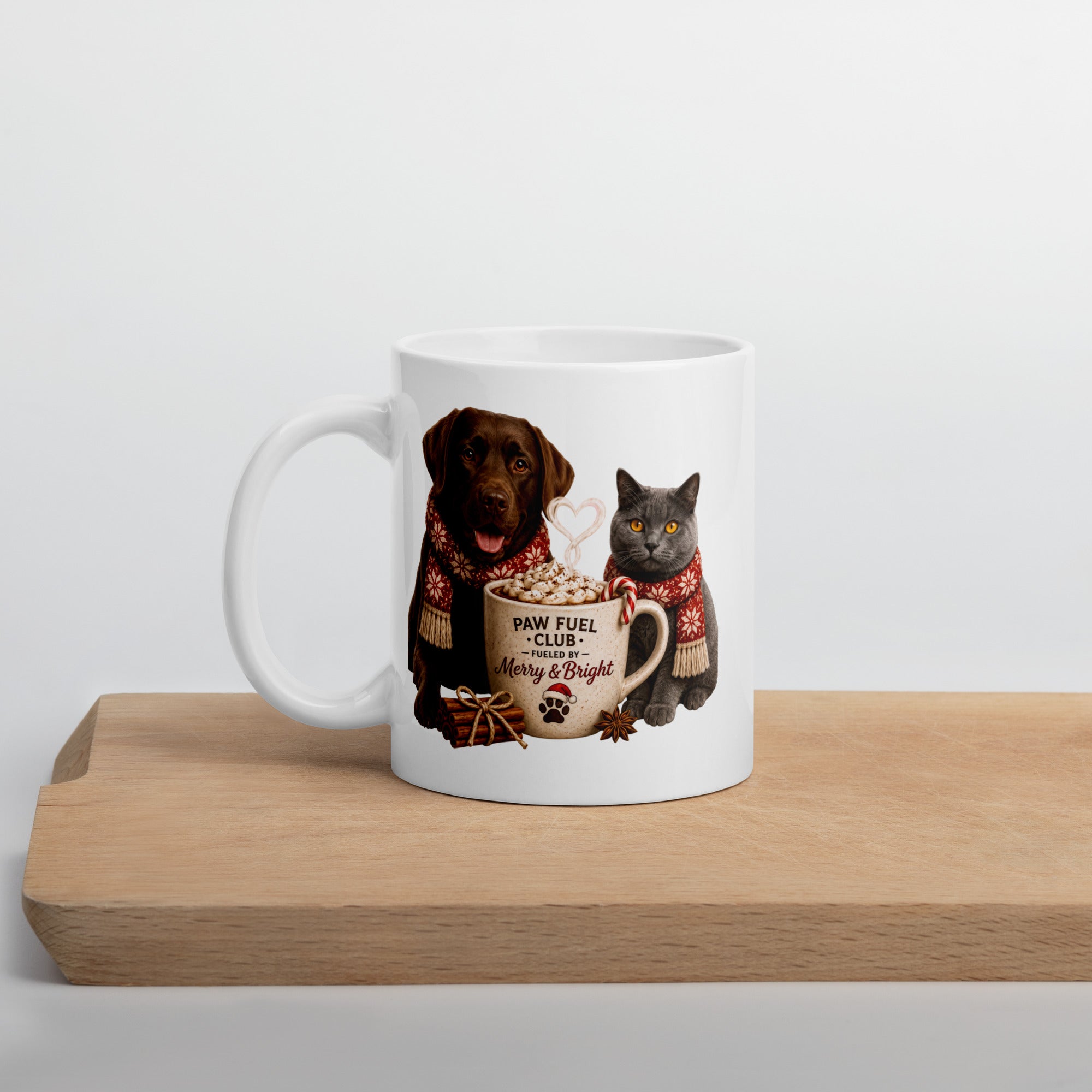 Paw Fuel Club Merry & Bright ceramic coffee mug featuring a Chocolate Labrador and British Shorthair cat wearing festive scarves beside a Christmas coffee mug by Paw Print Society.