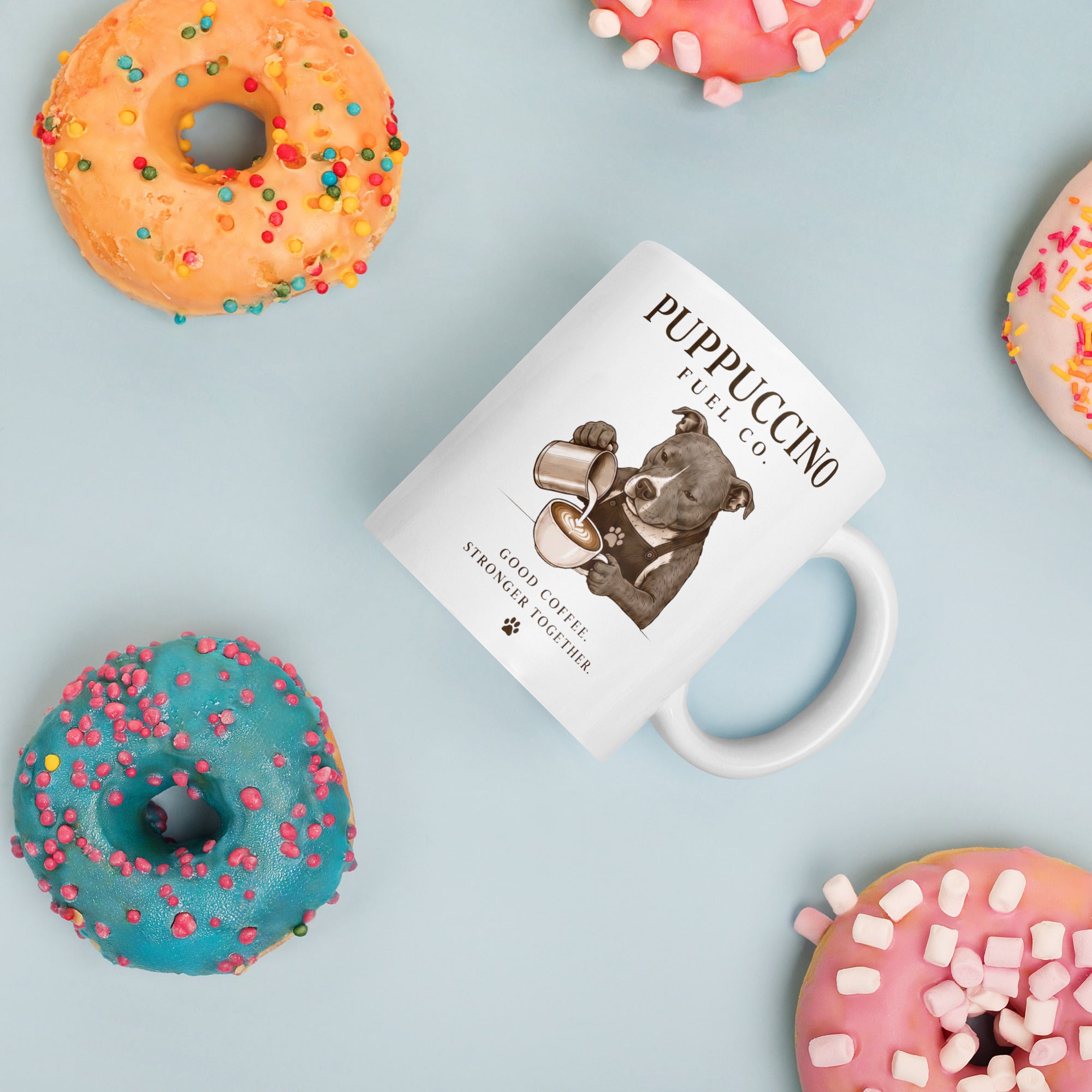 Mug with a staffordshire bull terrier design and text, surrounded by colorful donuts on a light blue background