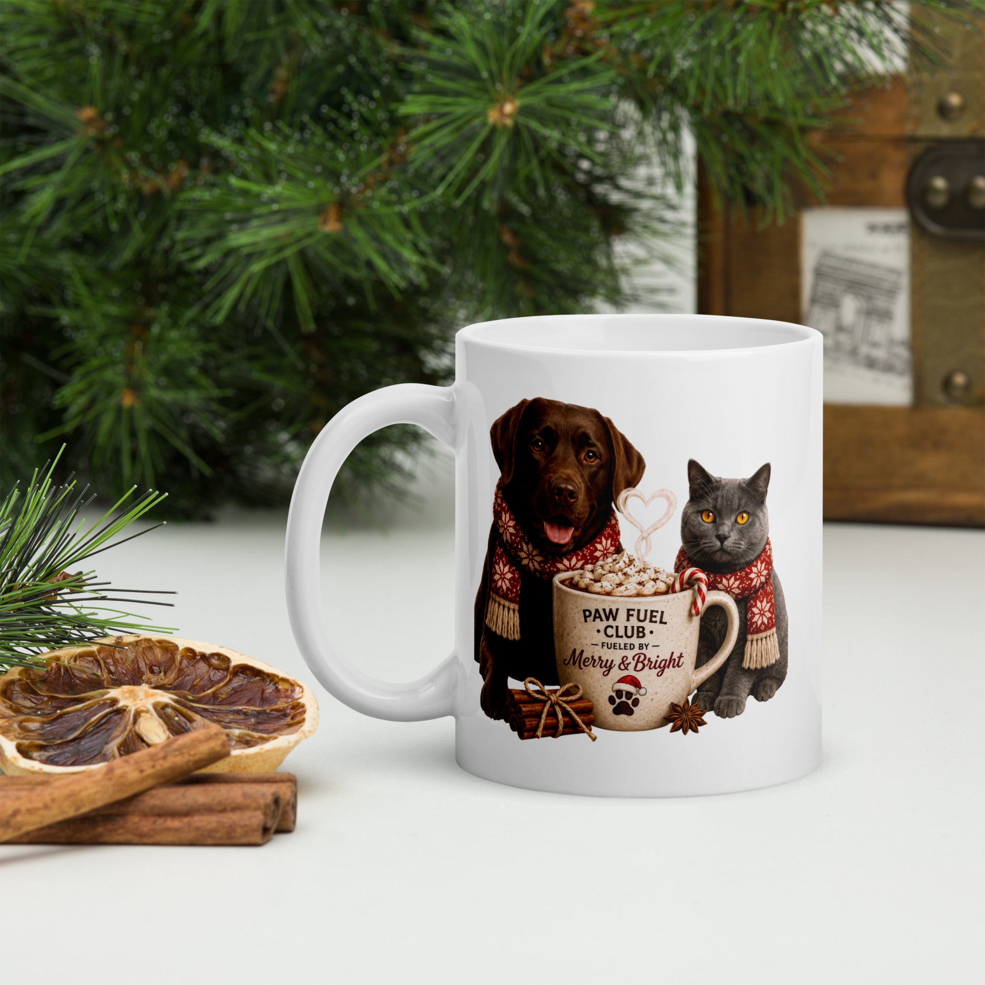 Paw Fuel Club Merry & Bright ceramic coffee mug featuring a Chocolate Labrador and British Shorthair cat wearing festive scarves beside a Christmas coffee mug by Paw Print Society.