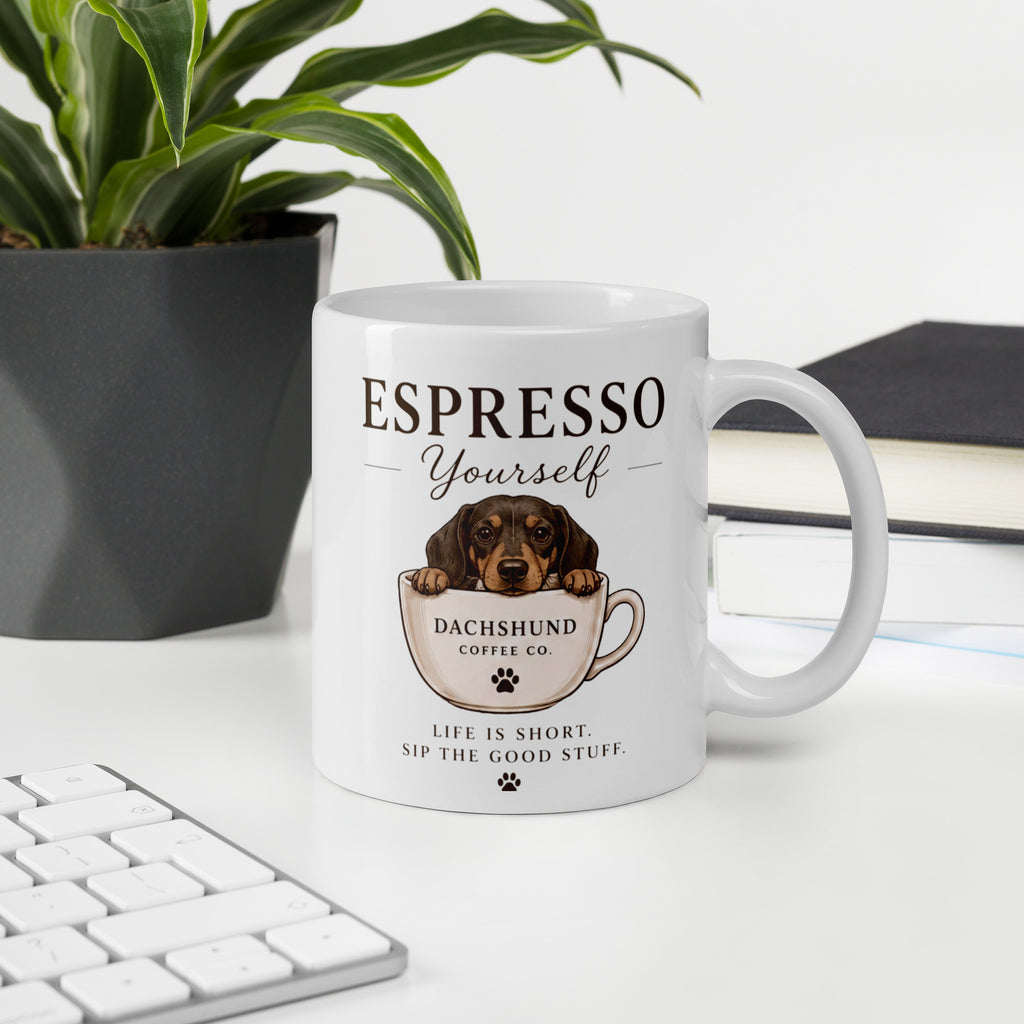 White ceramic coffee mug with a picture of a dachshund in a tea cup on it and the words Expresso Yourself sitting on a desk.